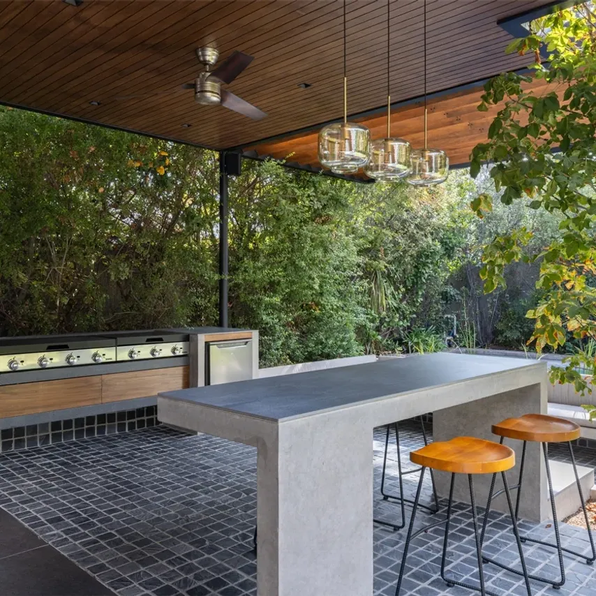 Render arquitectónico a vista aérea de una villa moderna y minimalista con fachada blanca. El exterior presenta un gran deck de madera clara, piscina rectangular y una pasarela que conecta a una zona de jacuzzi independiente, integrado en un paisaje natural y arbolado