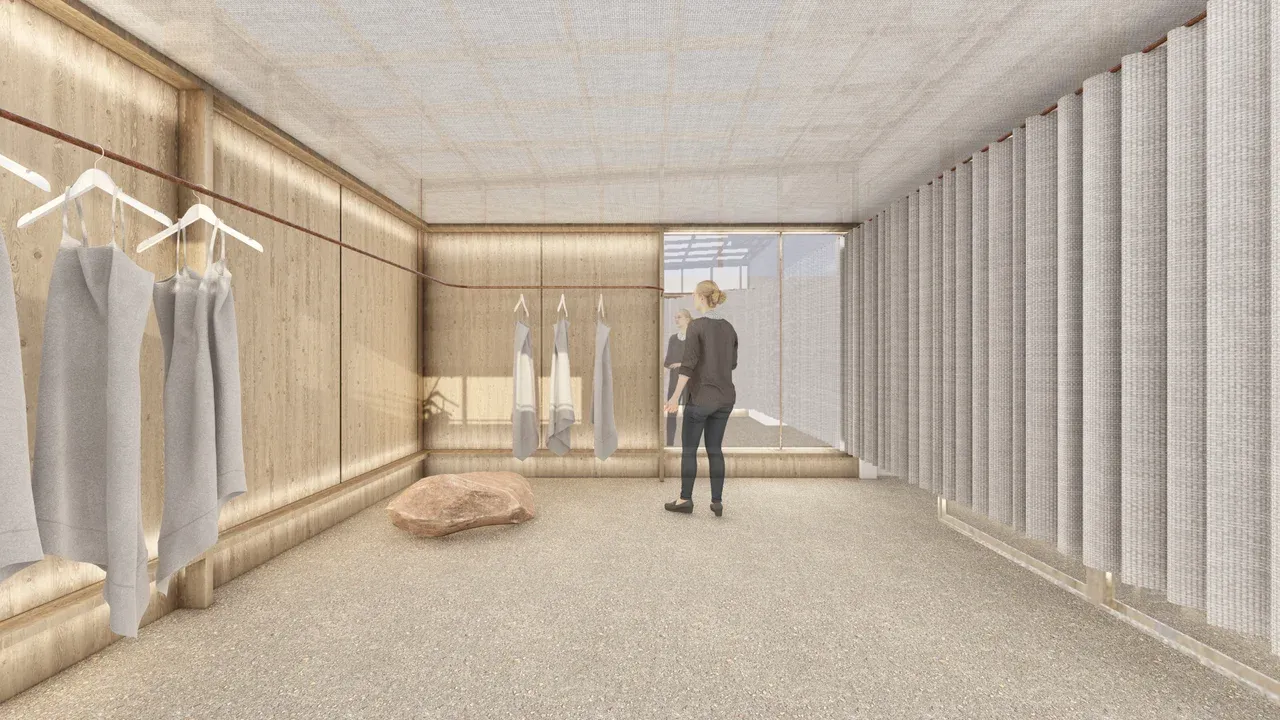 Render 3D de la zona de exhibición de la tienda Marrakesh en Vitacura. El diseño interior utiliza paredes de madera clara y techo de tela difusora para un ambiente cálido. A la derecha, se observa un probador definido por grandes cortinas plisadas de tela texturizada, con suelo de guijarros y una roca decorativa de color salmón
