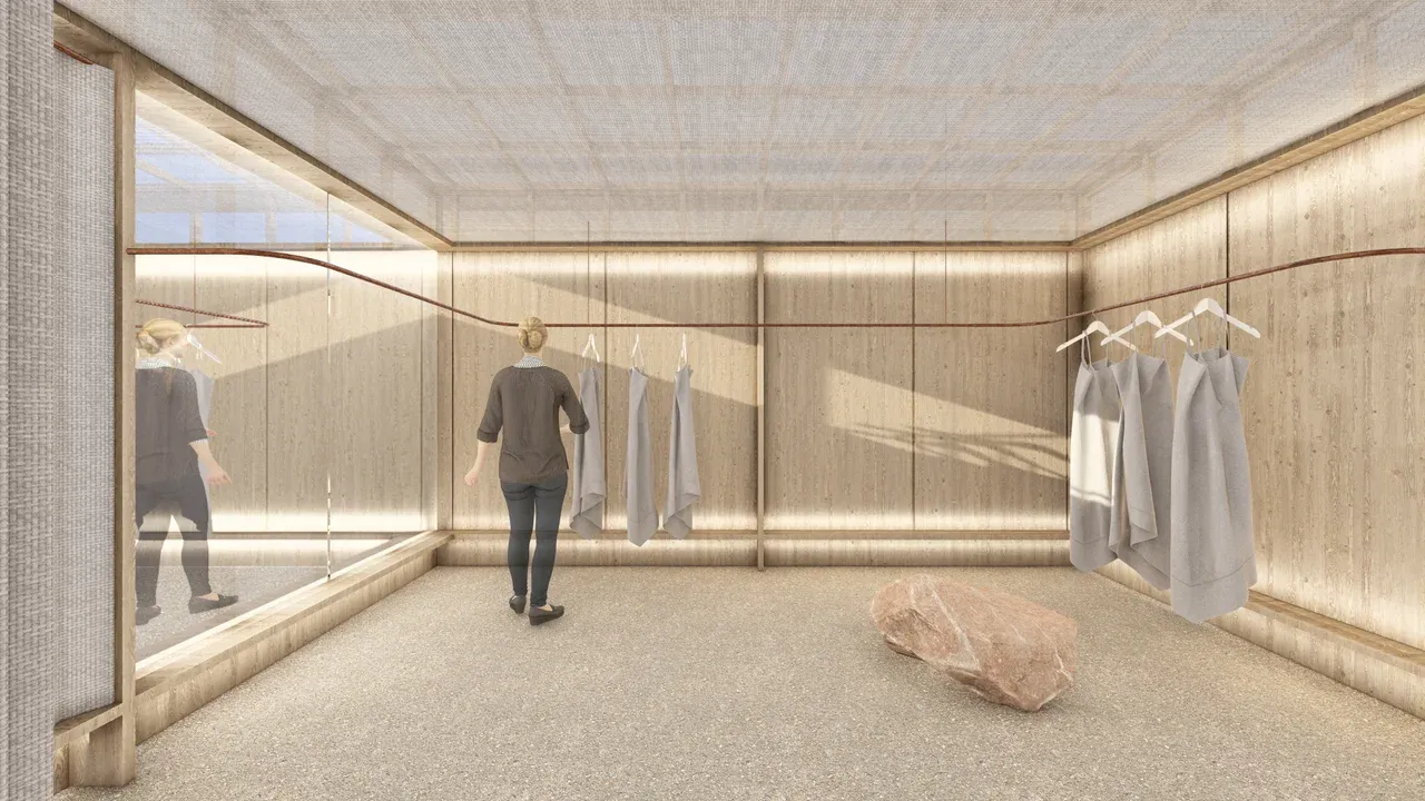 Render de diseño interior para la tienda Marrakesh en Vitacura. El espacio expositivo presenta paredes de tablones de madera clara, un techo de tela difusora y un sistema minimalista de rieles color óxido para colgar ropa. El piso es de guijarros claros y hay una roca decorativa al centro